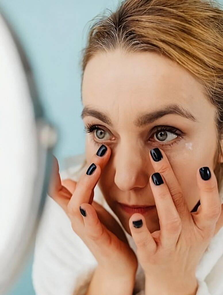 Middle-aged woman looking in the mirror wanting to know how to lose face fat.