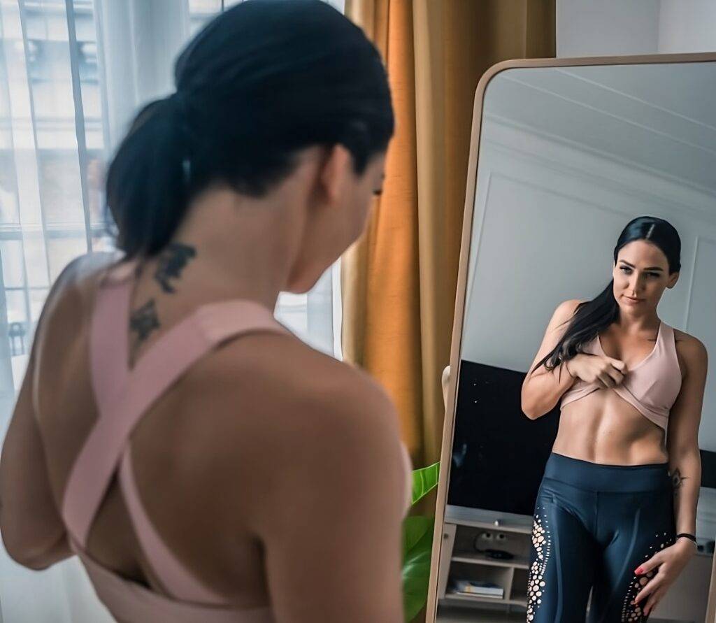 Woman looking at her abs after doing core strengthening exercises to lose weight.